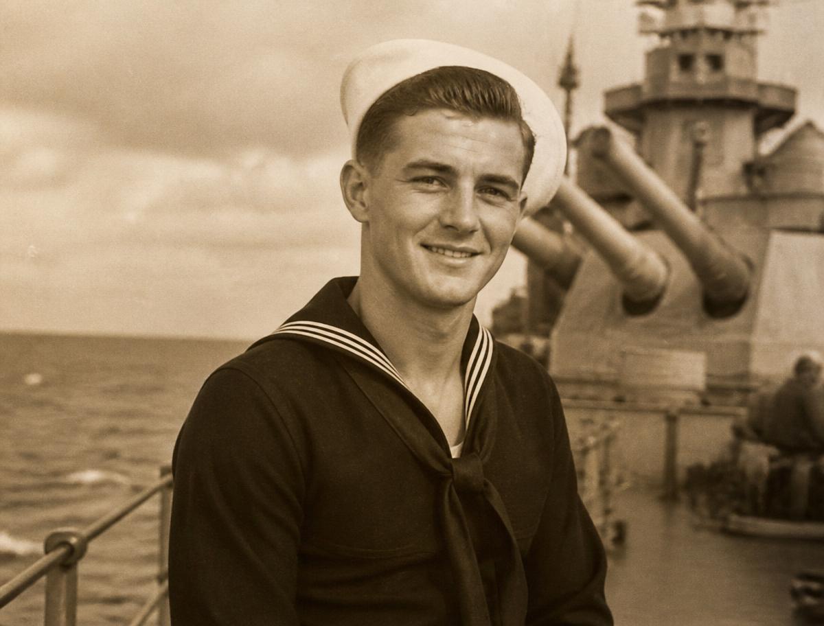 Sepia portrait of a young U.S. Navy sailor on the deck of a battleship